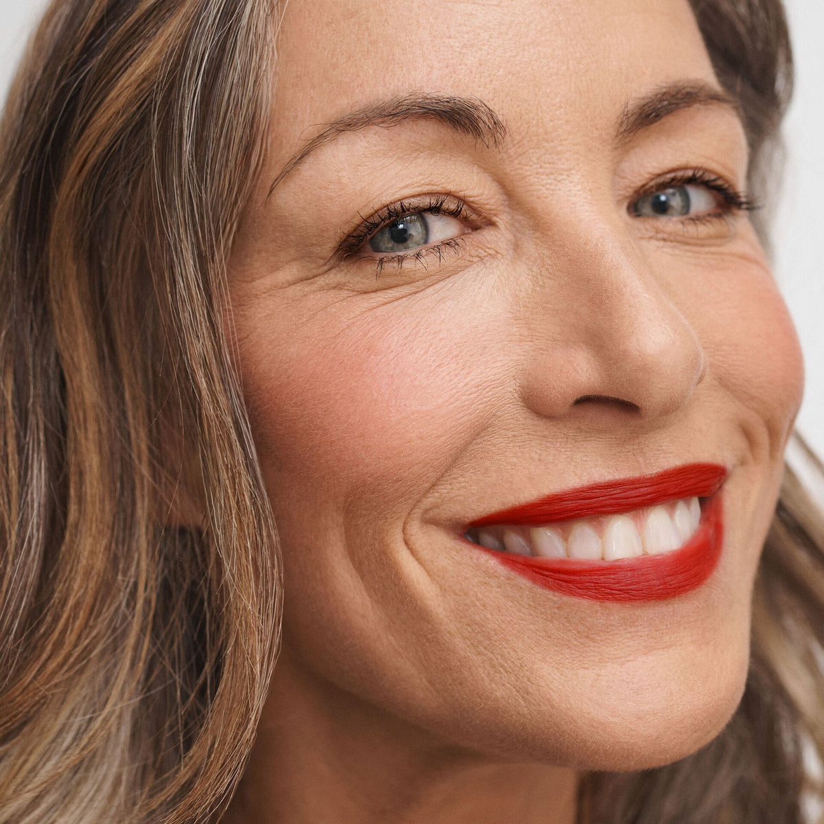 model with medium tone skin wearing No Makeup Makeup Creme classic lipstick in original red