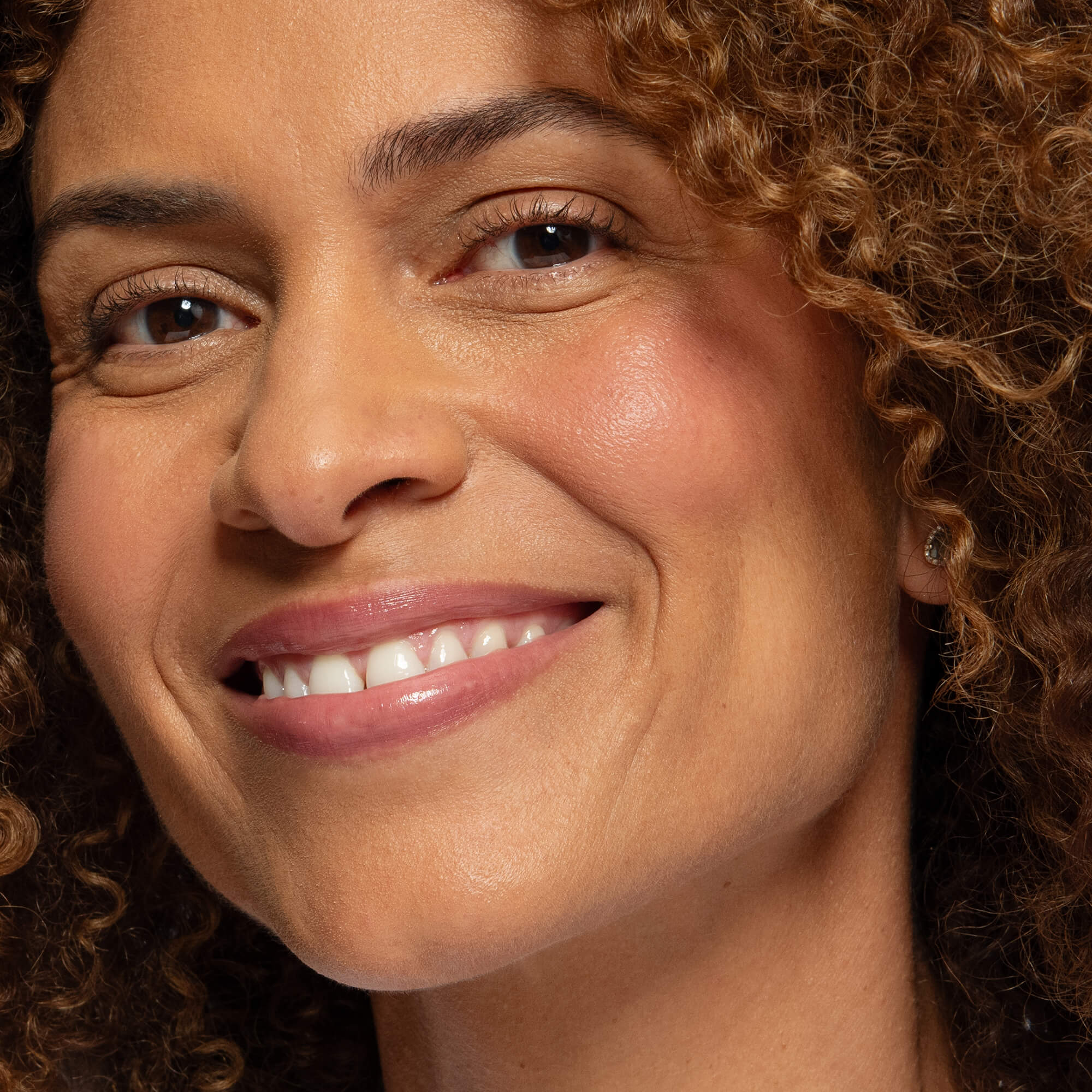 Close-up of a tanned skin woman wearing pink blush on cheeks and lips