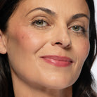 Close-up of a woman with medium skin wearing plum blush shade on cheeks and lips