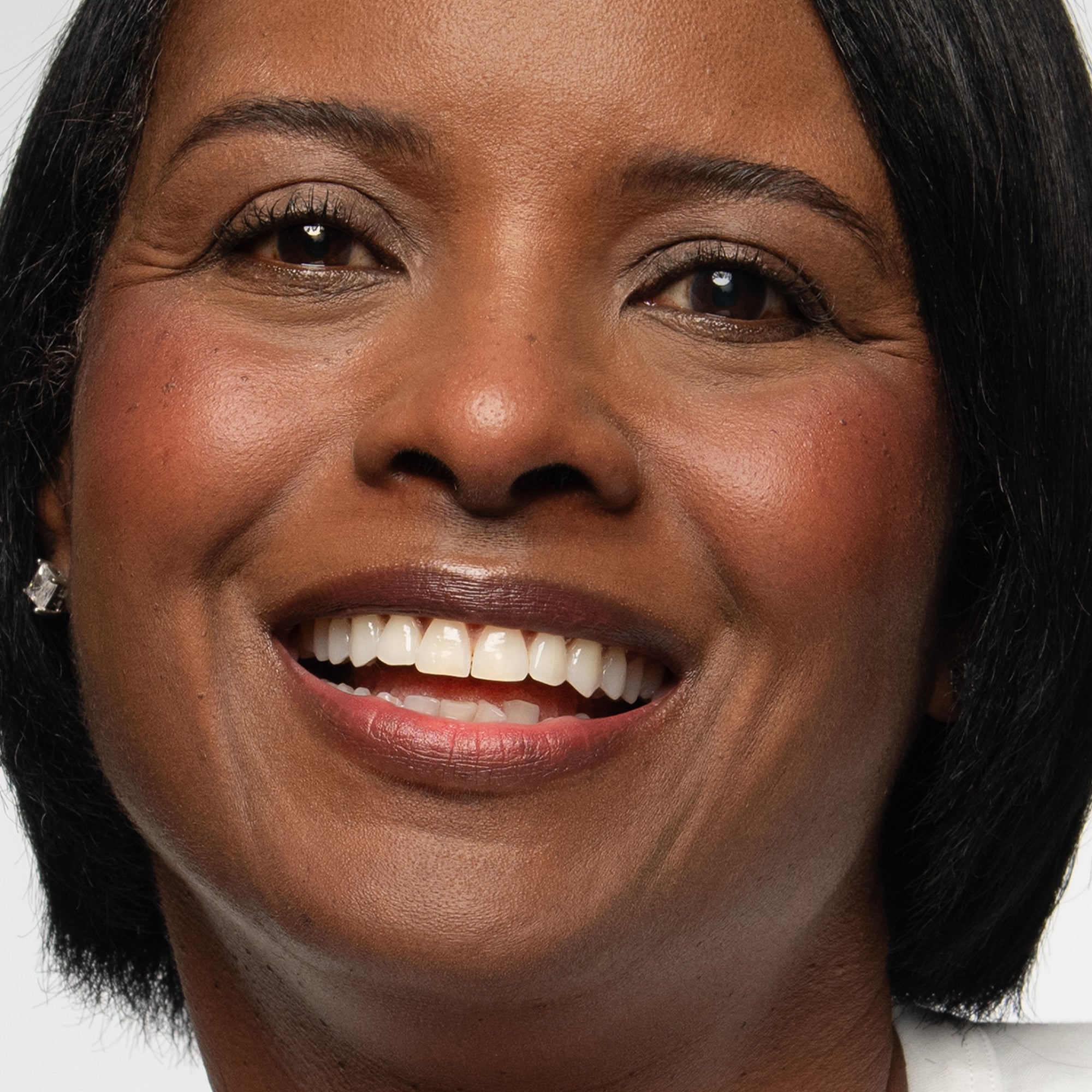 Close-up of a woman with dark skin wearing plum blush shade on cheeks and lips