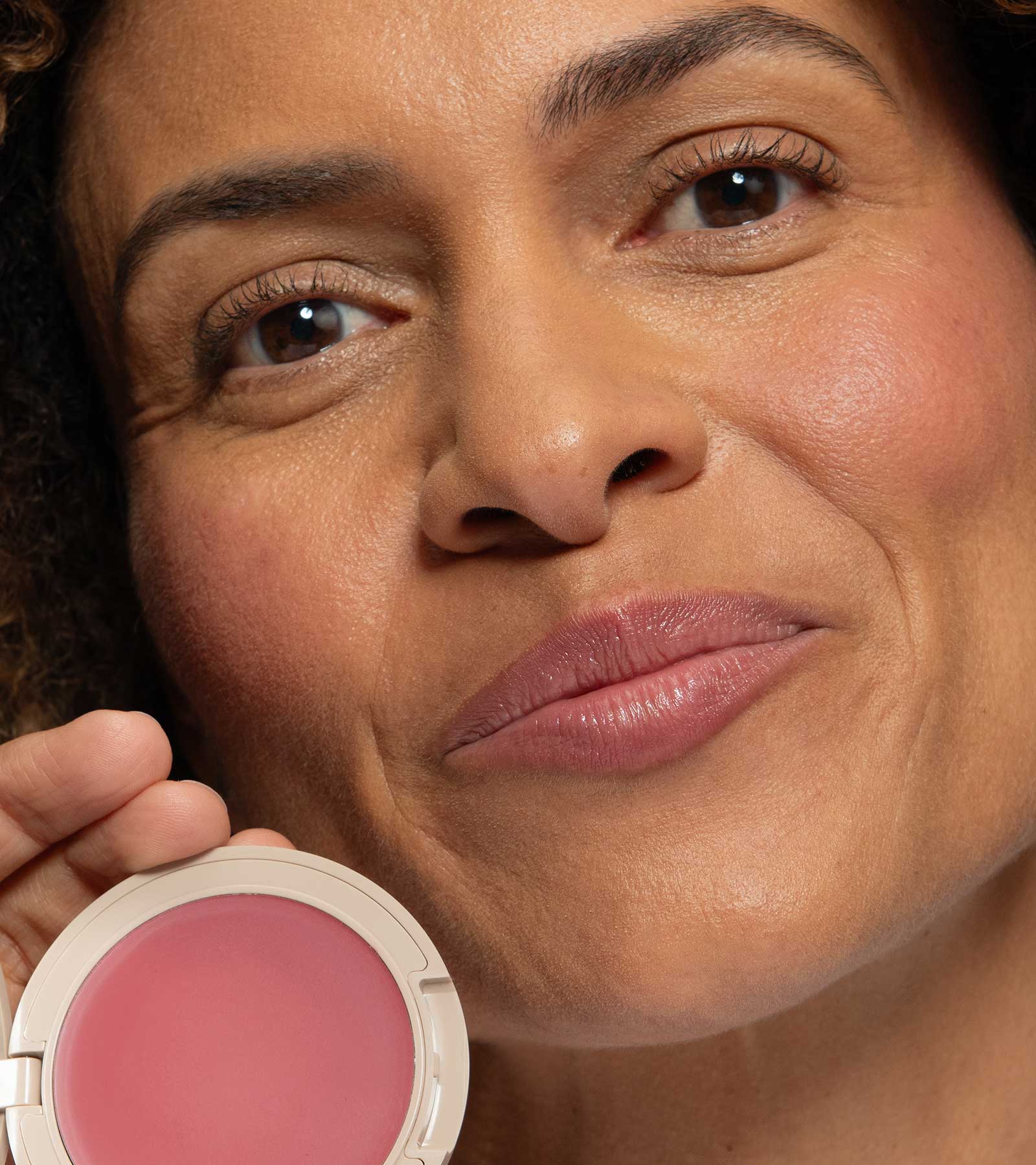Close-up of a woman holding a pink blush compact