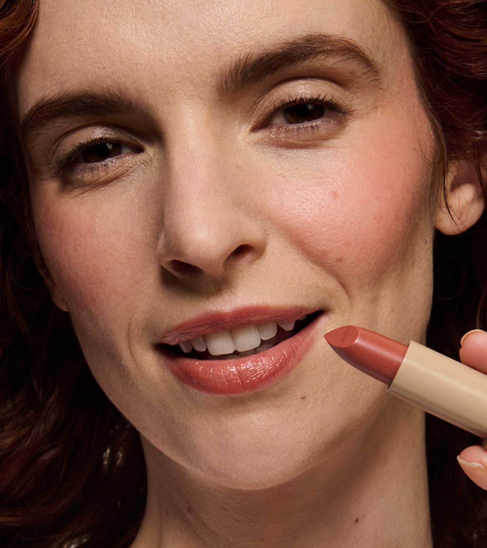 model wearing and holding peach 02 lipstick shade