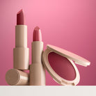 Plum lipstick and blush with beige applicator on a plum background