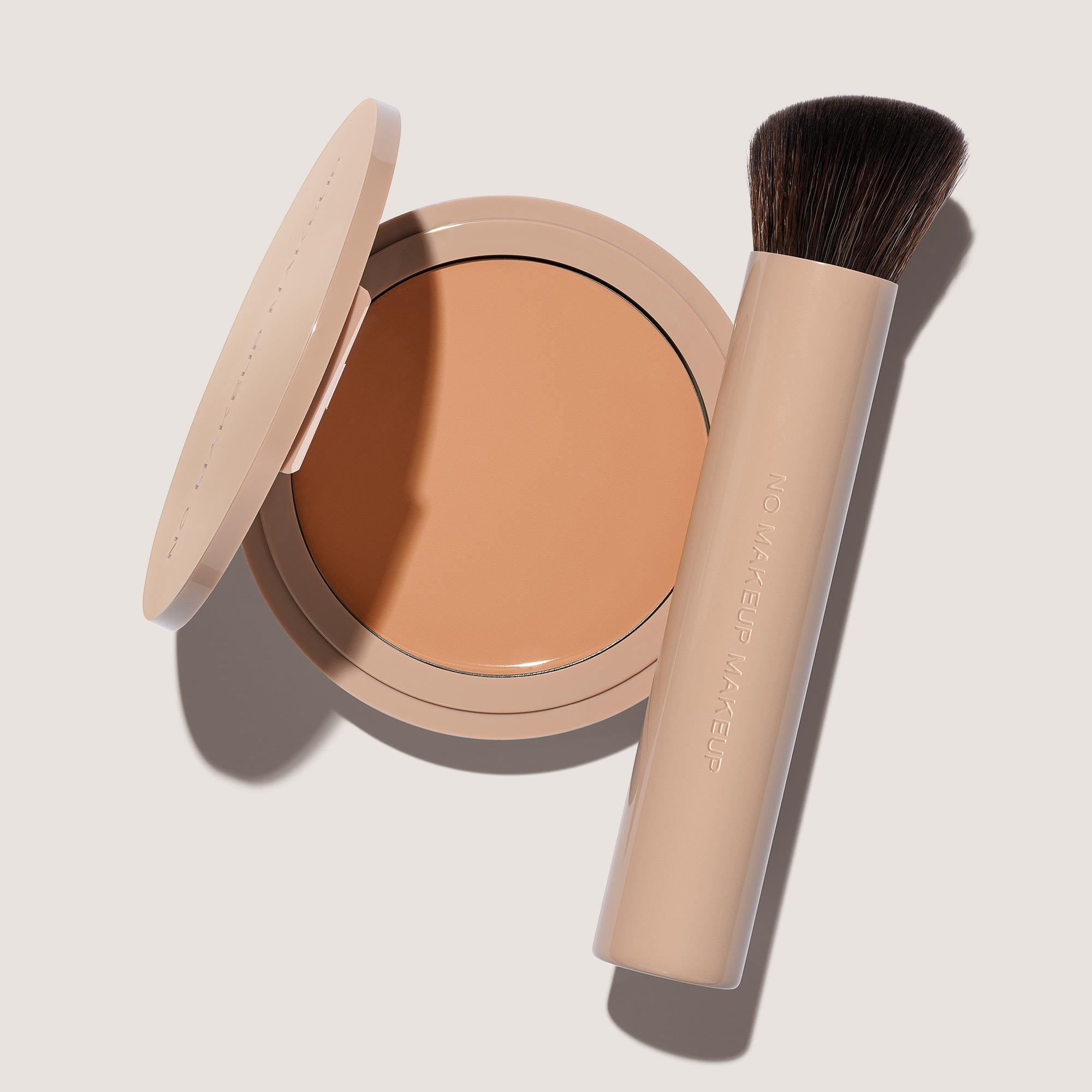An open FlexShade Foundation by No Makeup Makeup compact in Light Medium and a brush