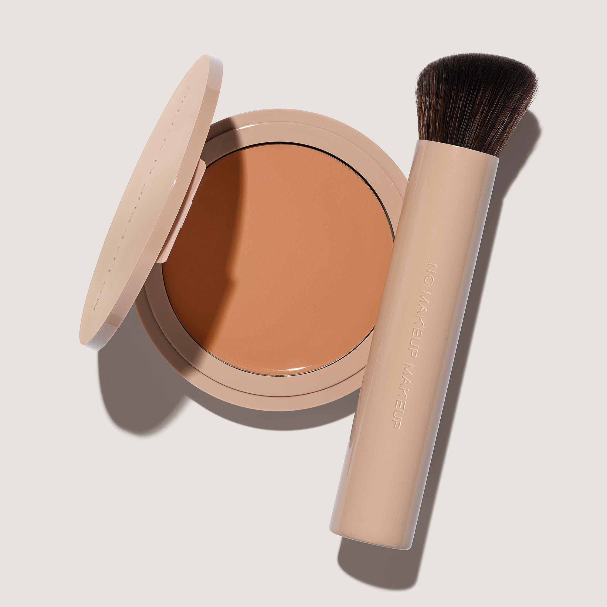 An open FlexShade Foundation by No Makeup Makeup compact in Medium and a brush with the Oprah Daily Beauty O-Wards 2024 seal