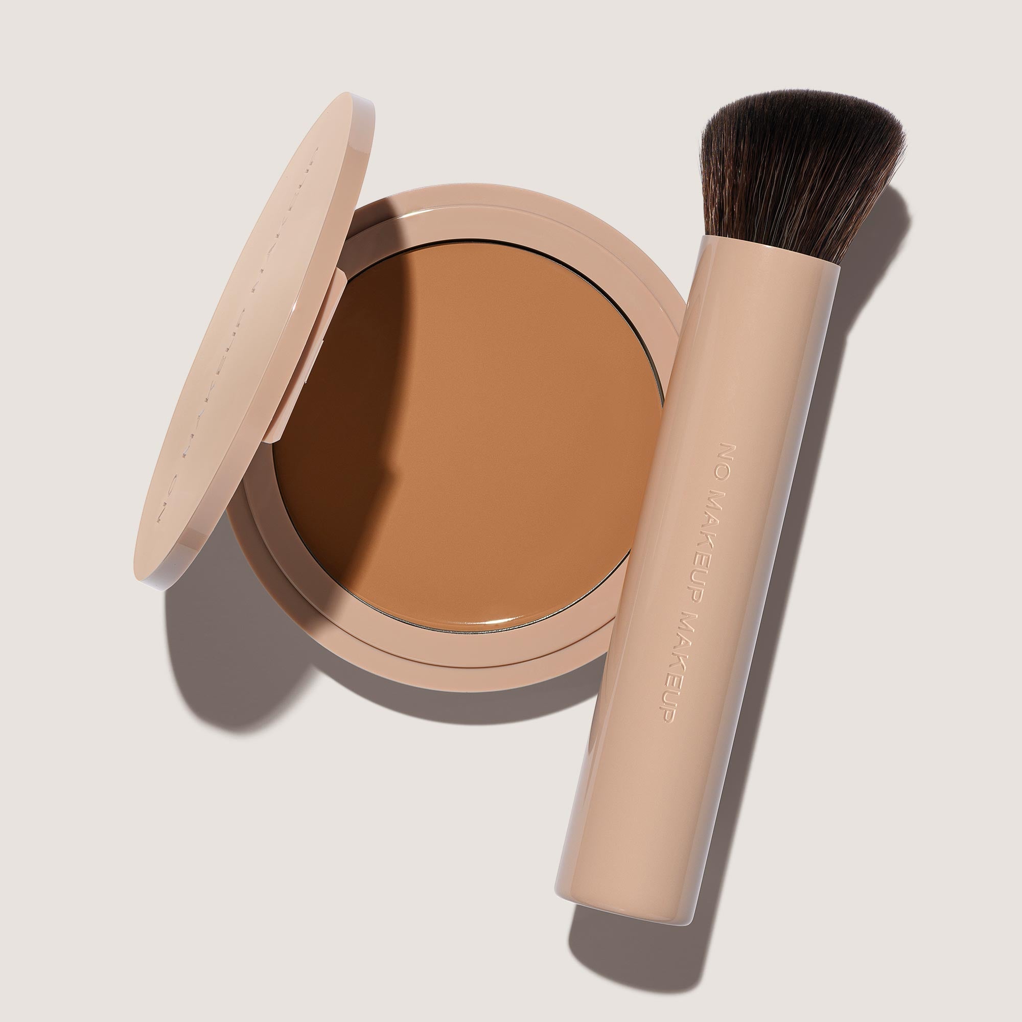 An open FlexShade Foundation by No Makeup Makeup compact in Tan and a brush with the Oprah Daily Beauty O-Wards 2024 seal