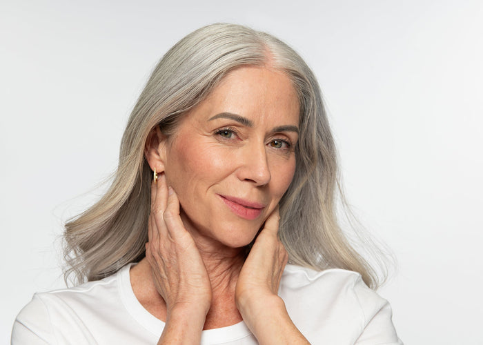 Smiling Mature Model Wearing No Makeup Makeup Foundation and Blush on a neutral background. 