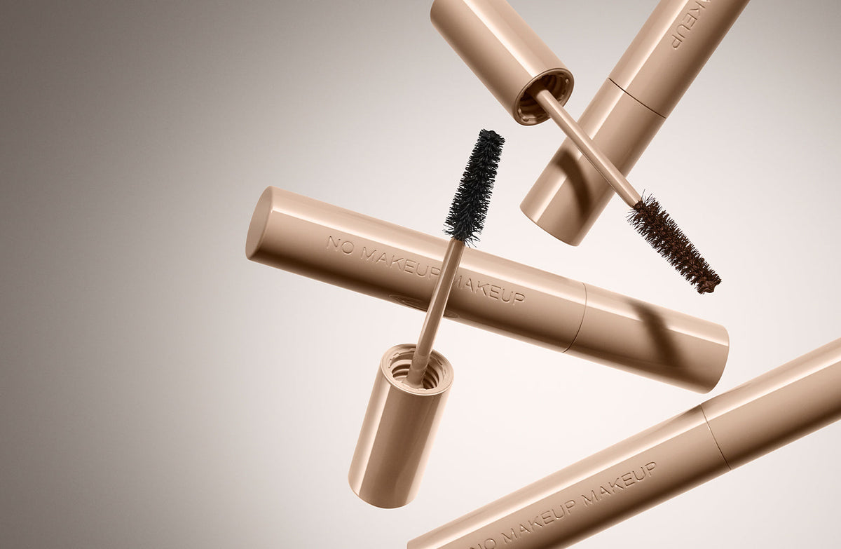 Multiple No Makeup Makeup mascara tubes in champagne gold with brushes showing formula texture