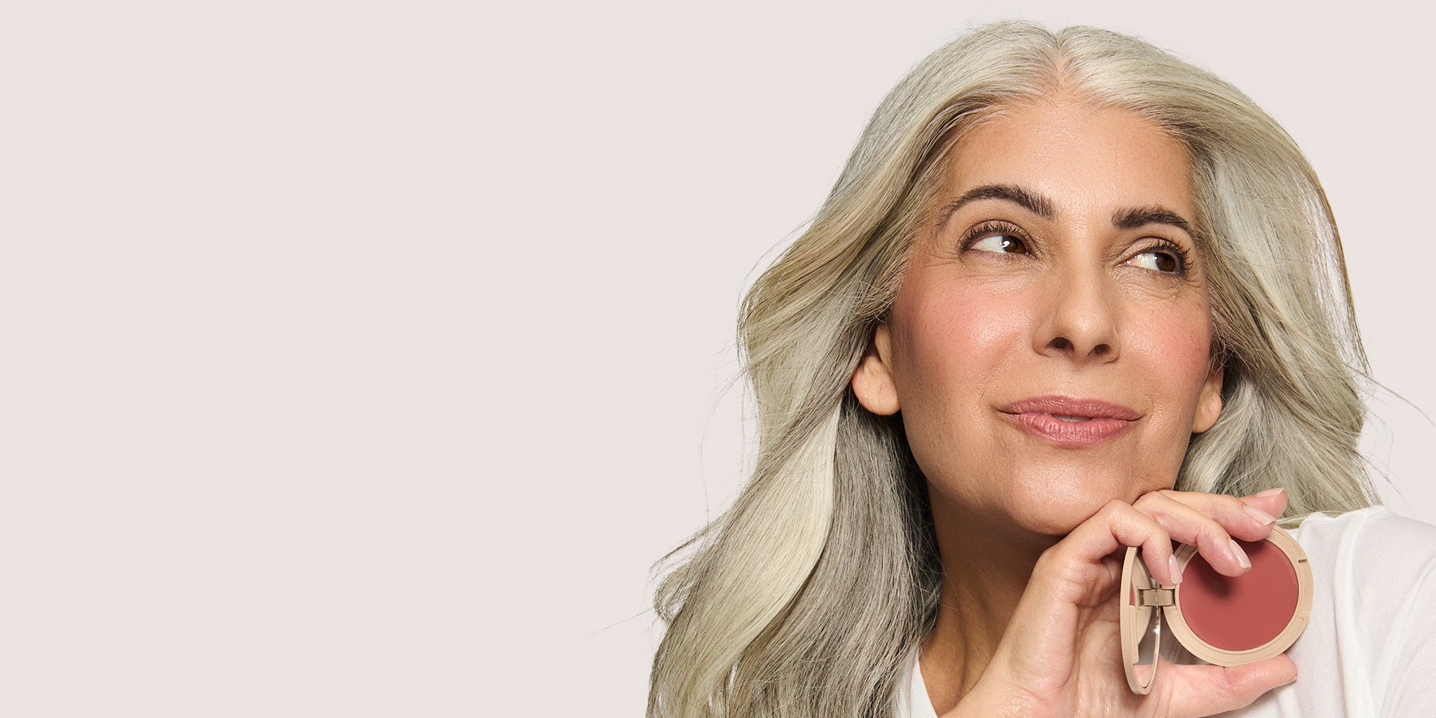 No Makeup Makeup – Close-up of a woman holding a pink blush compact, natural minimal makeup