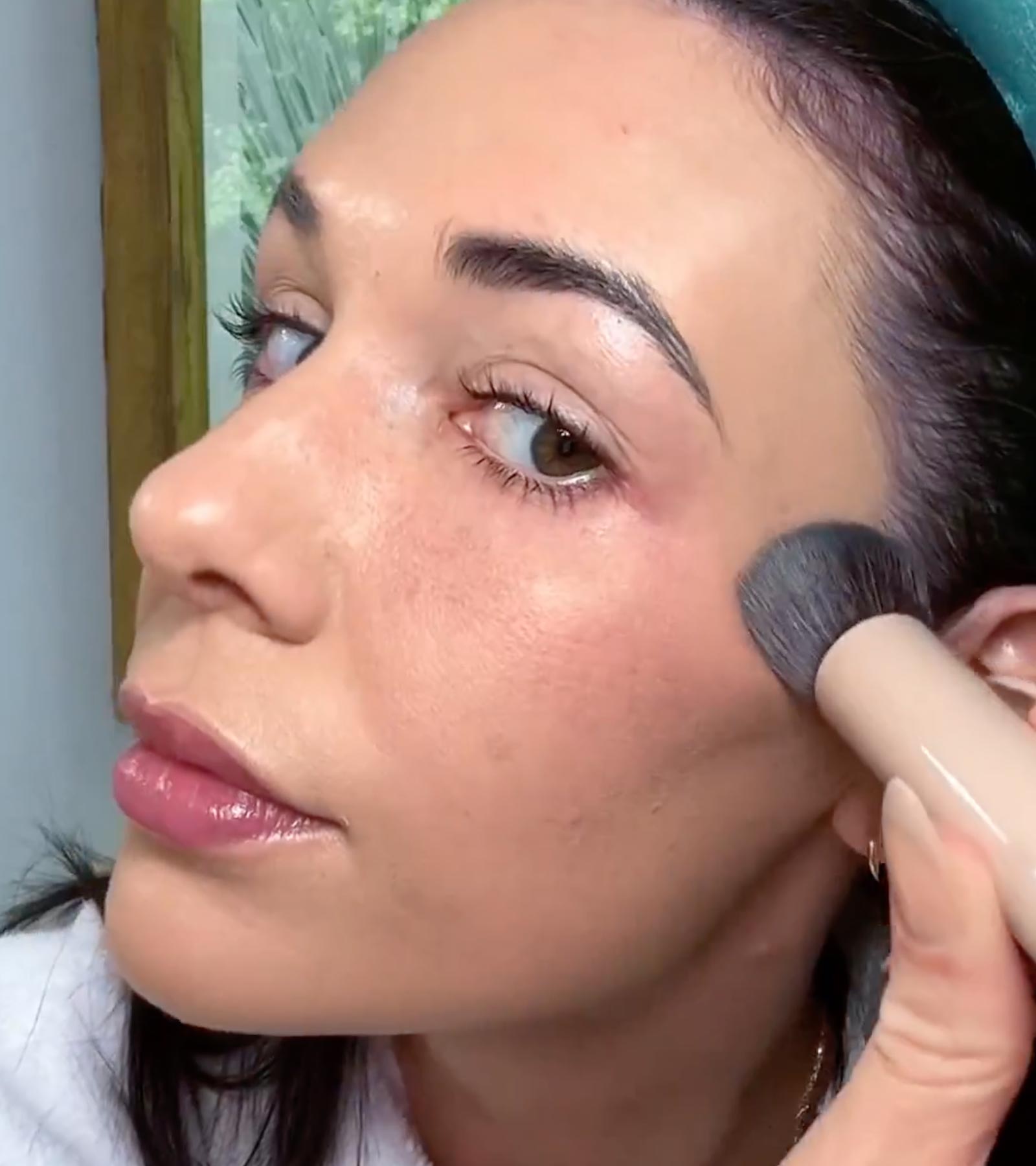 Person applying foundation with a brush to their face