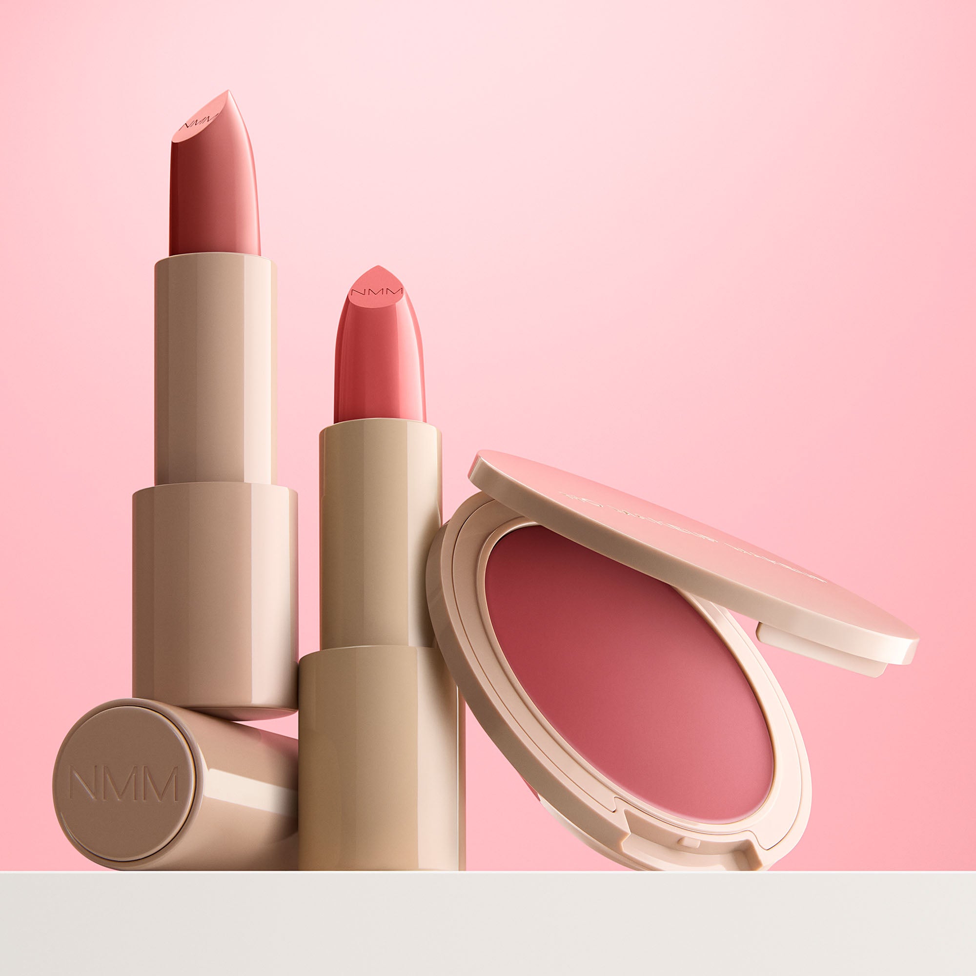 Pink lipsticks and a blush on a pink background