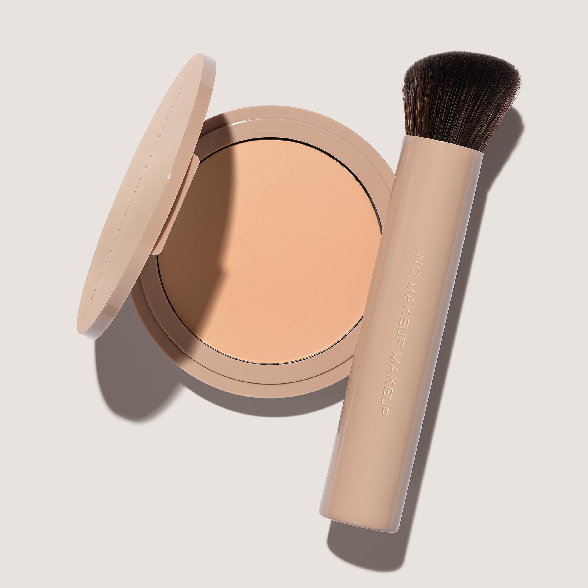 An open FlexShade Foundation by No Makeup Makeup compact in Fair and a brush