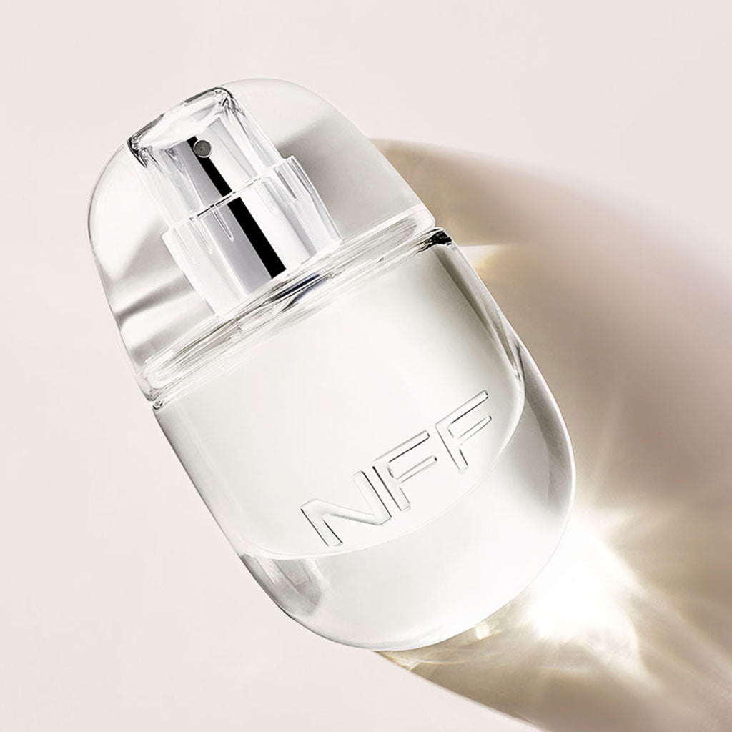 Clear perfume bottle on a light pink background